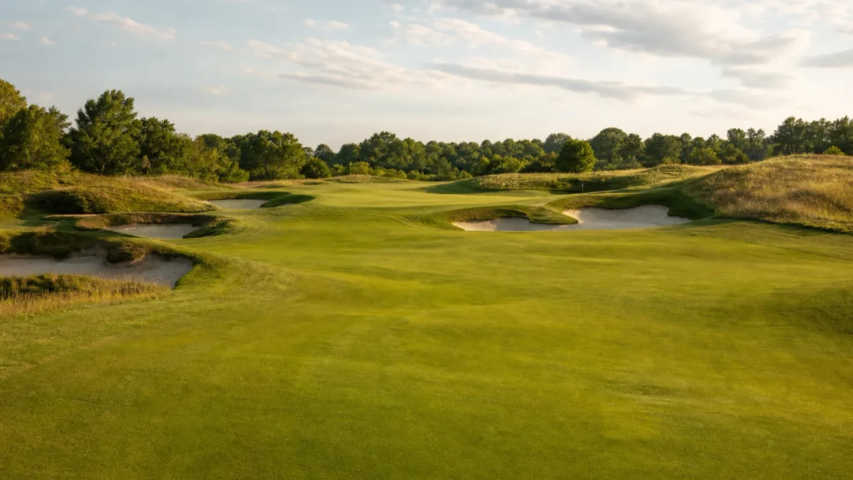 Golfbana med fairway, bunkrar och green i varmt dagsljus