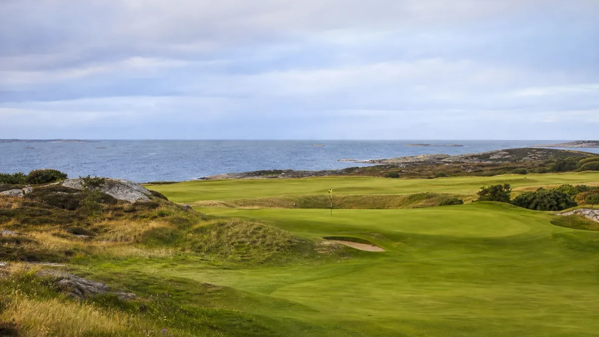 Kustnära svensk golfbana med fairway och green